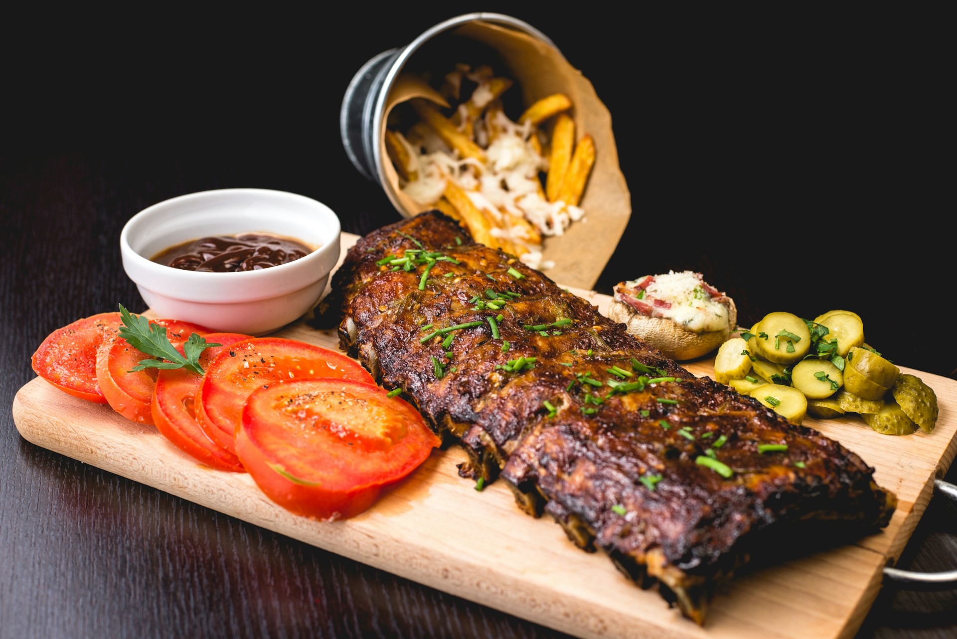 A picture of a well seasoned grilled ribs with tomatoes, sauce, and fies