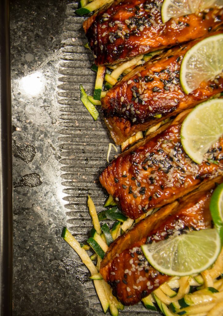 A plate of juicy grilled salmon with some lemon slices on the top