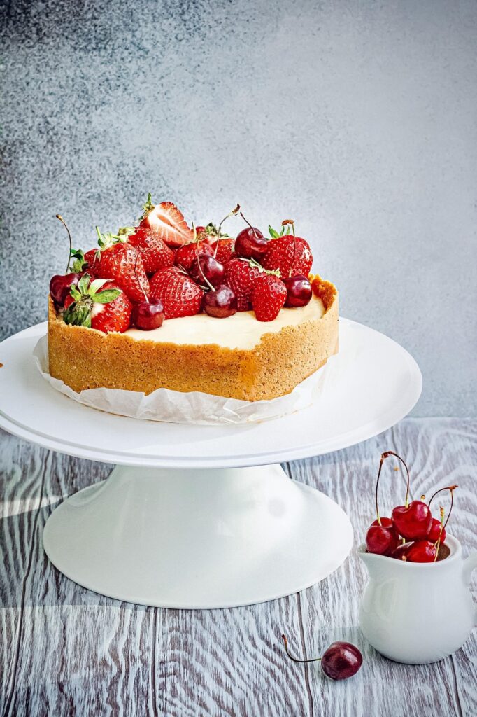 Creamy strawberry cake A creamy cake in the shape of a heart with strawberry on top of it, presented beautifully on a white plate