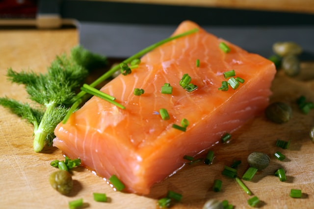 A piece of uncooked salmon over a wooden plate